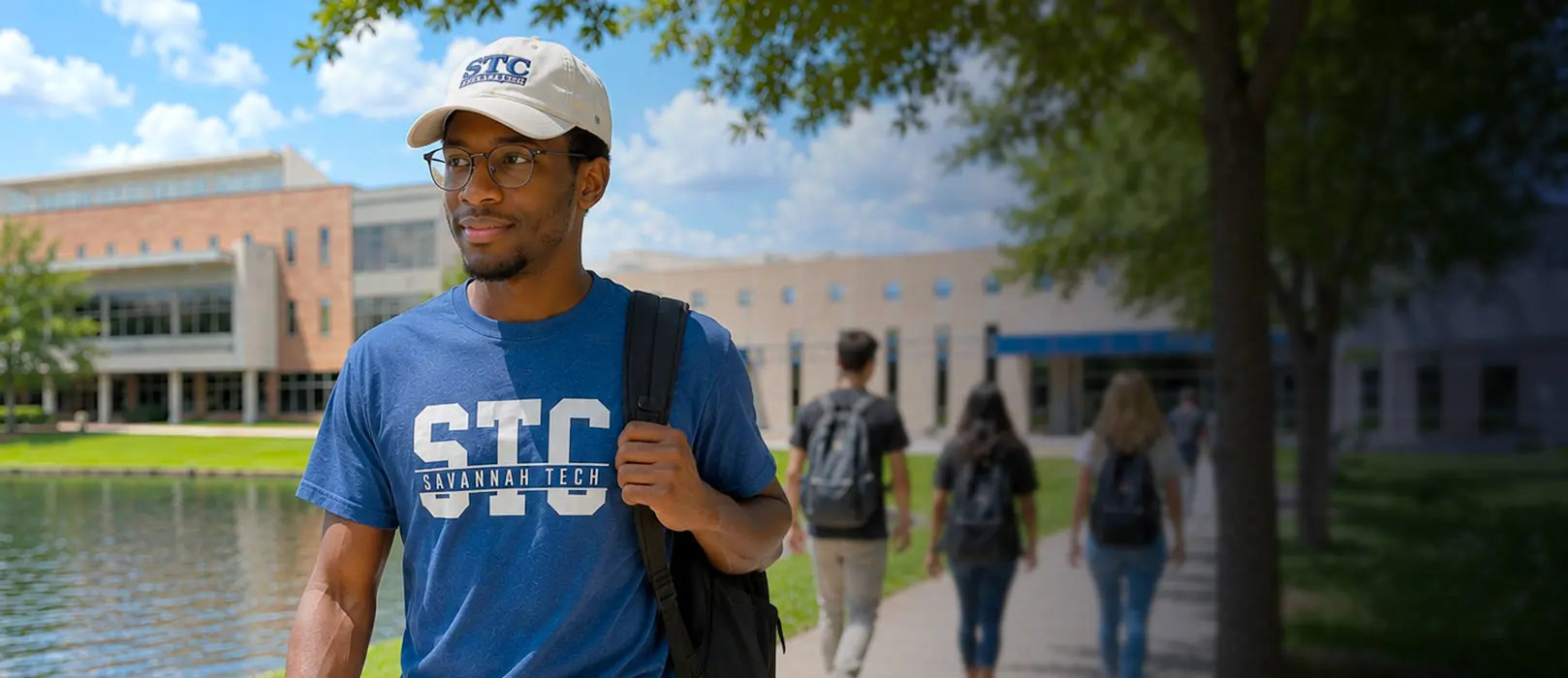 Student walking on campus wearing STC shirt and hat